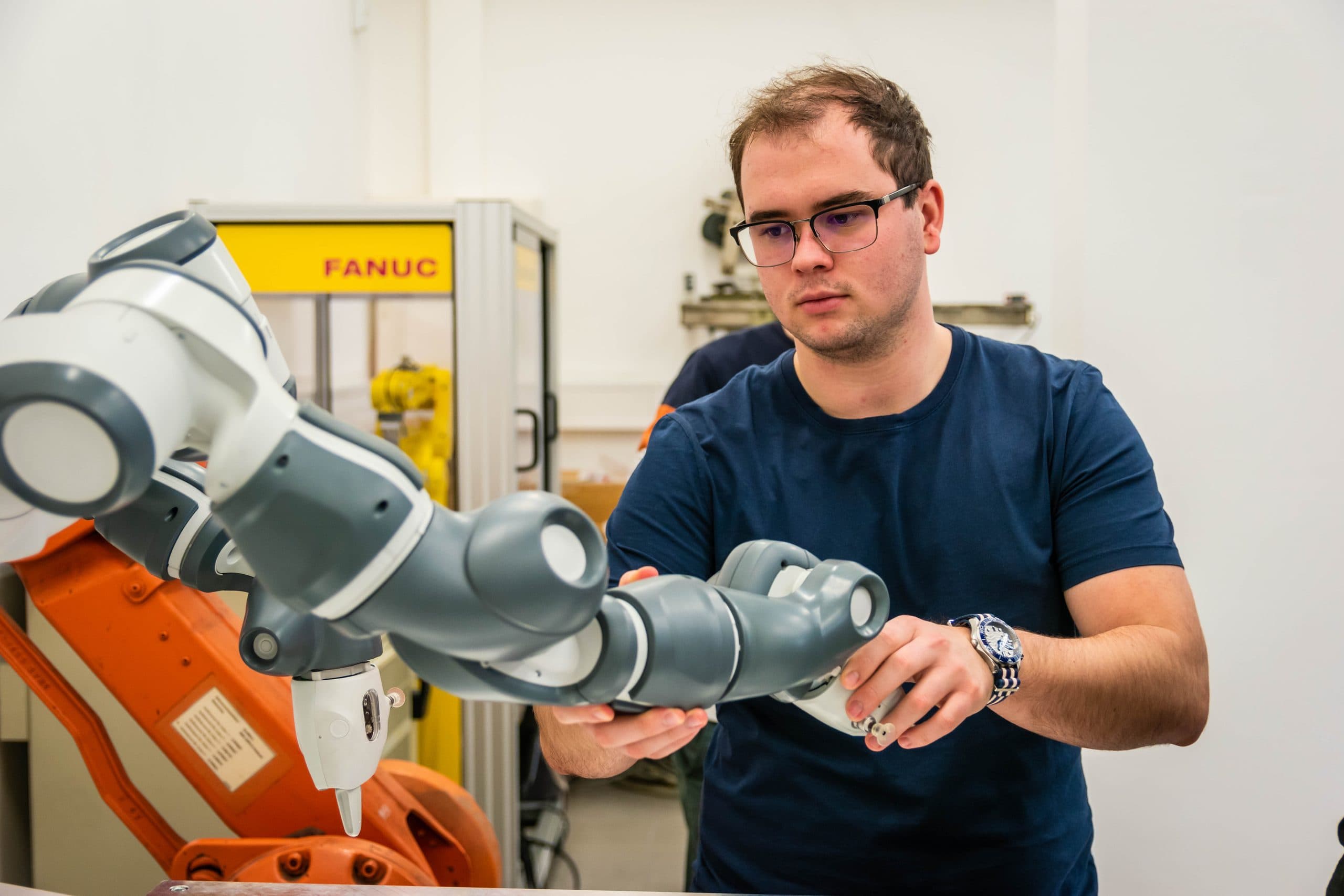 Estudante programando braço robótico industrial