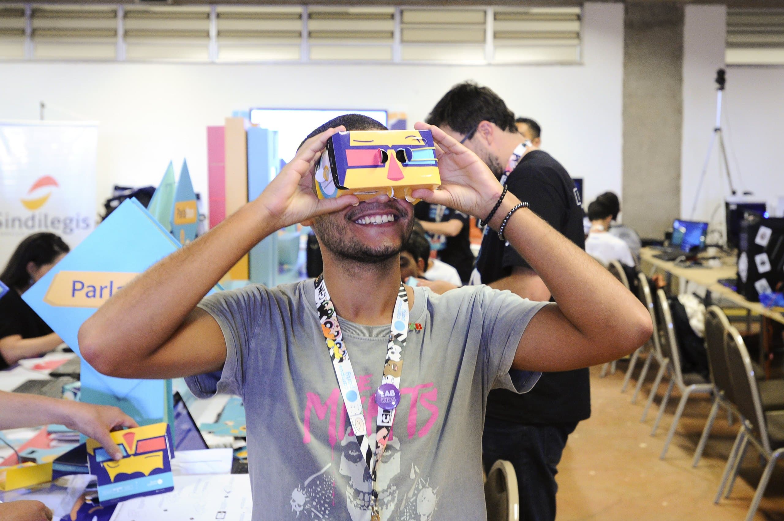 Jovem participante rindo com óculos de realidade virtual de papelão em evento de tecnologia no Brasil